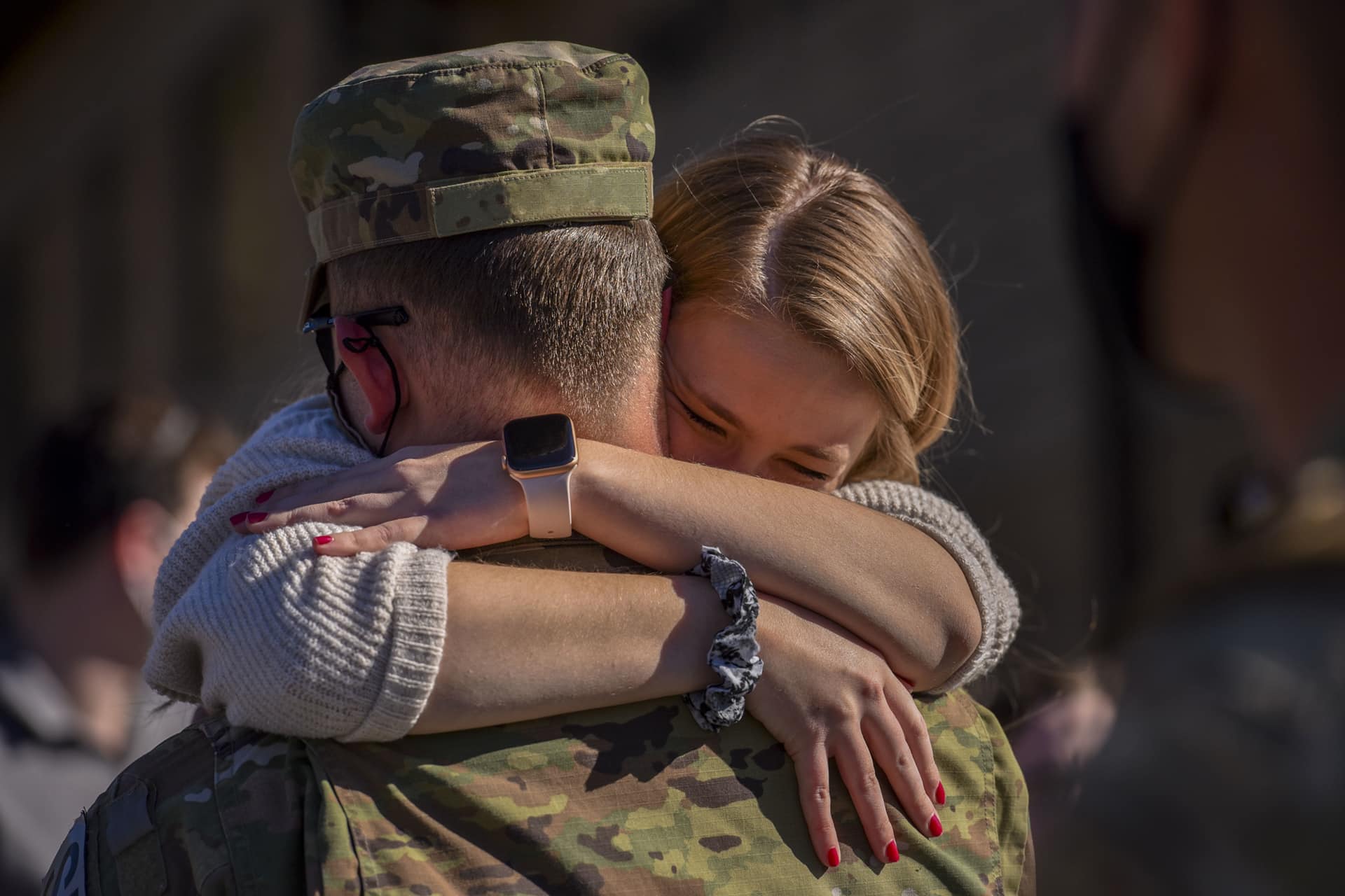 teen daughter hugs her father who is in military uniform